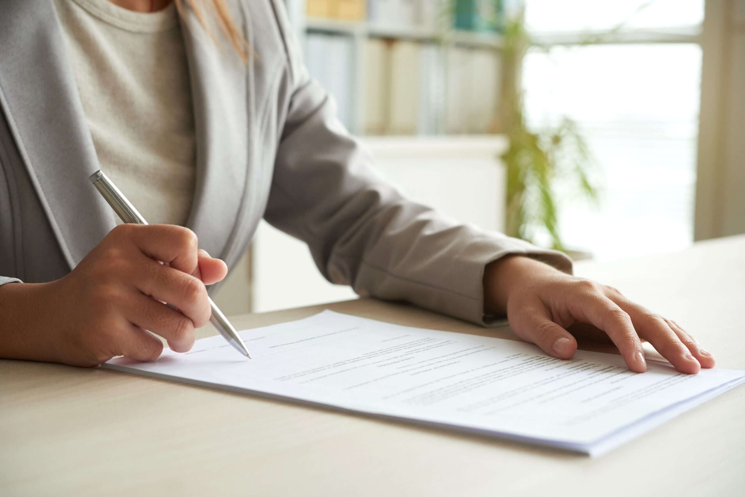 Hands of business entrepreneur signing document on her table