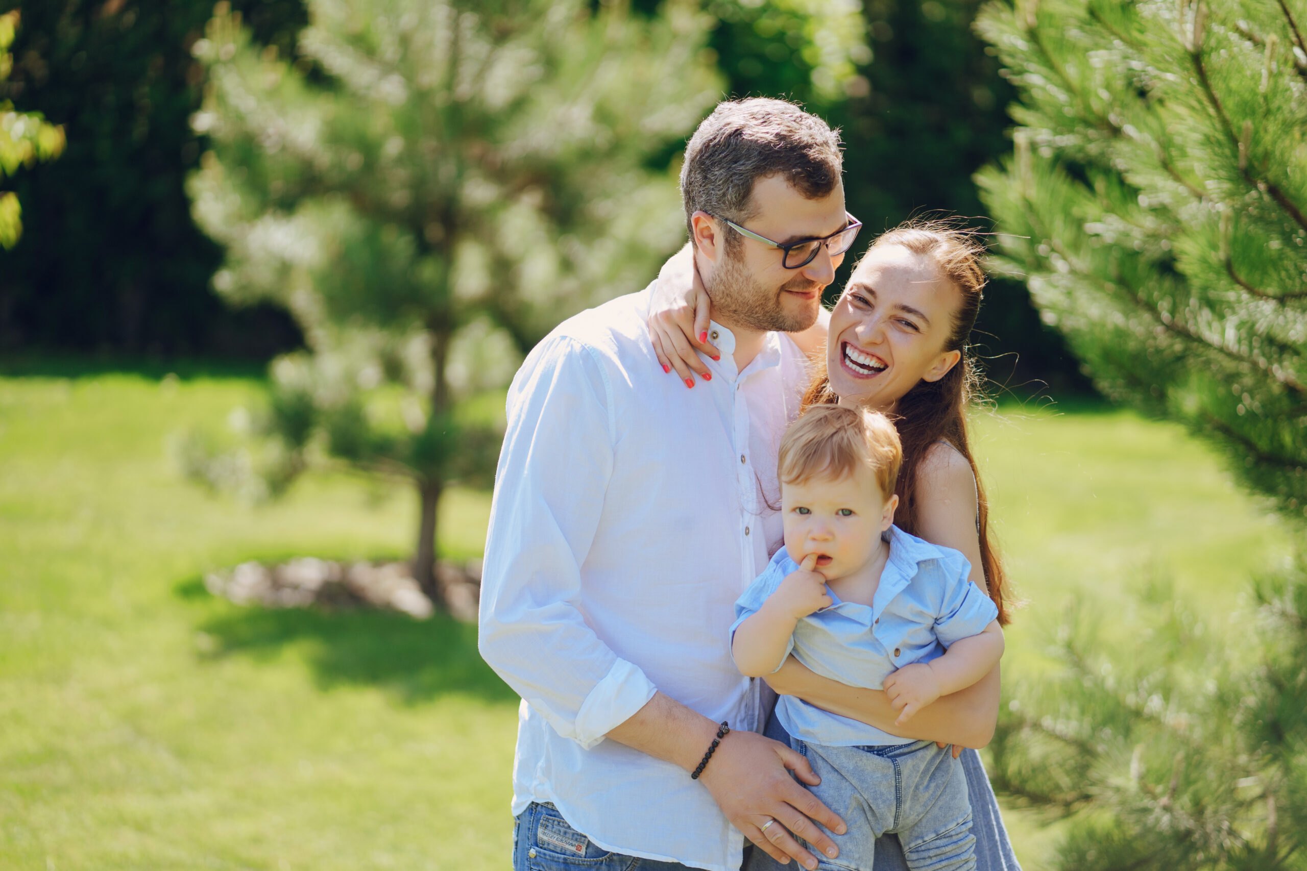 beautiful long-haired mother in a long blue dress in sunny summer forest walks with his beautiful child and handsome man
